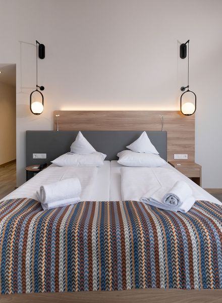 Hotelzimmer mit Doppelbett und modernen Lampen